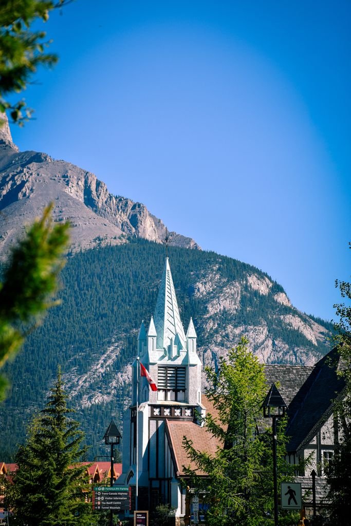 A picturesque view of Banff featuring a distinctive church spire against mountain scenery.