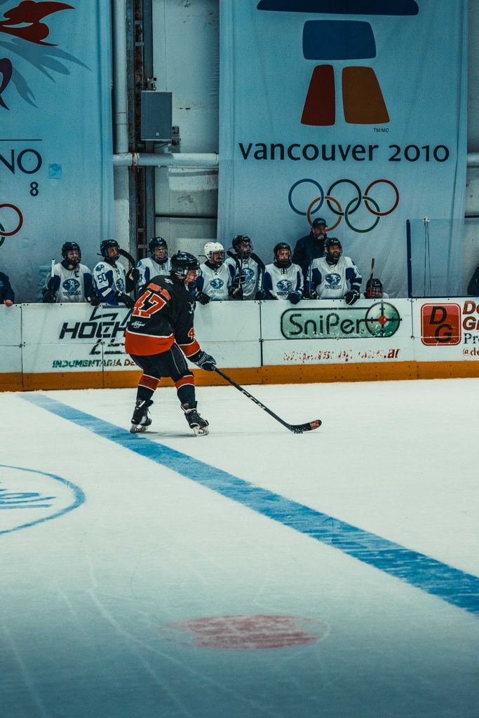 Ice hockey player in action at an indoor rink with Vancouver 2010 Olympic signage.