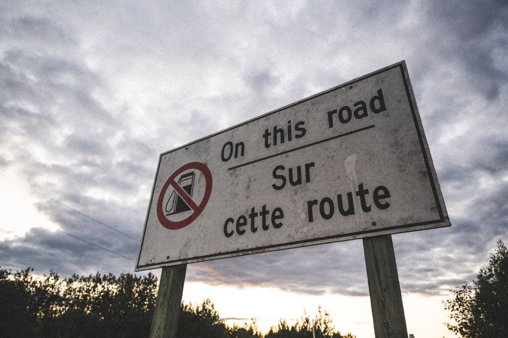 Low-angle shot of a bilingual road warning sign against a cloudy sky in Smooth Rock Falls, Canada.