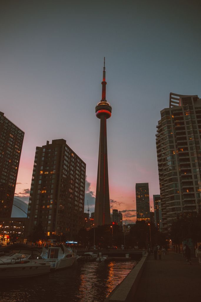 Stunning view of the CN Tower and Toronto skyline at twilight with city lights and silhouettes.